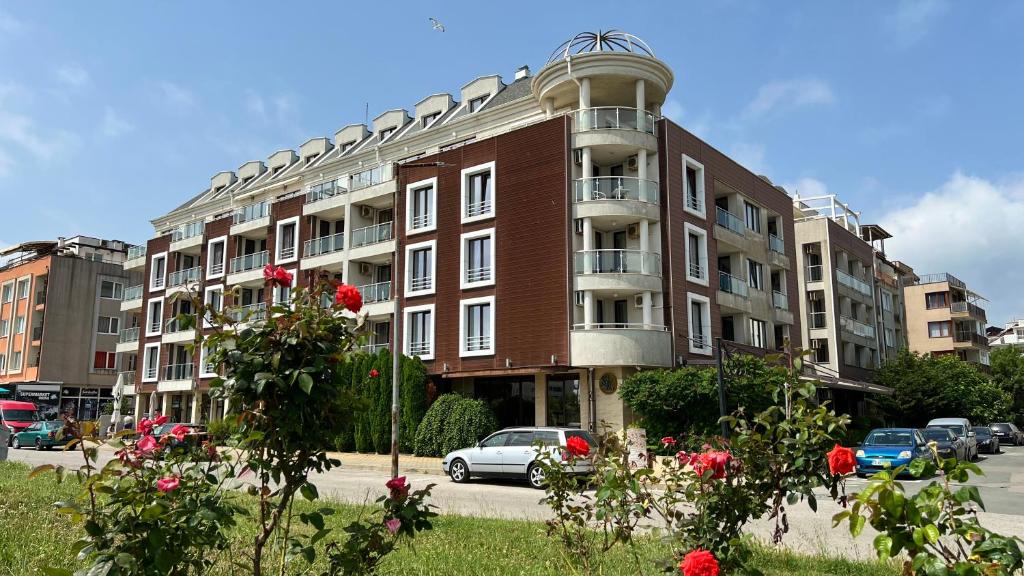 a large building with cars parked in front of it at Stamopolulux директен изглед към морето in Primorsko