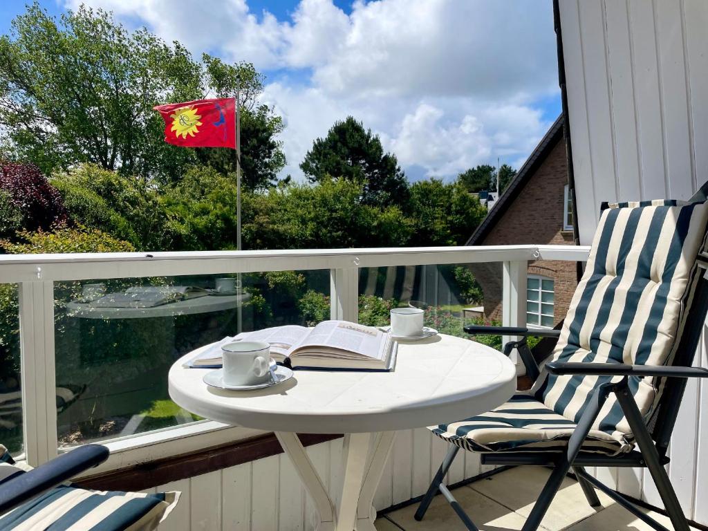 Una mesa y sillas en un balcón con una bandera. en Amaris-Sylt, en Munkmarsch