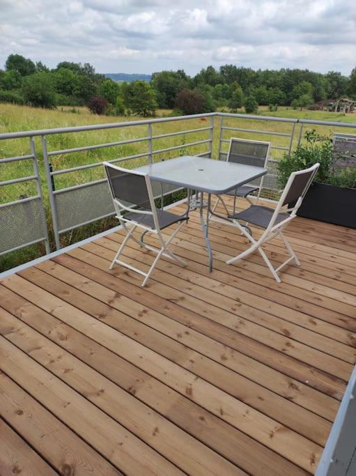 une table et deux chaises sur une terrasse en bois dans l'établissement Un air de campagne, à Orliénas