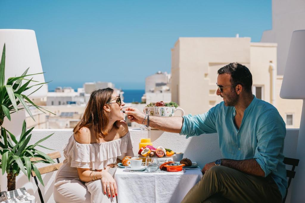 Un hombre alimentando a una mujer con un plato de comida. en Giorgio Boutique Hotel, en Sliema