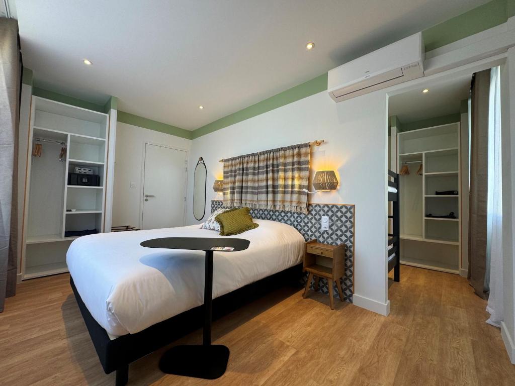 a bedroom with a bed and a table in it at Hôtel du Midi Plage in Palavas-les-Flots