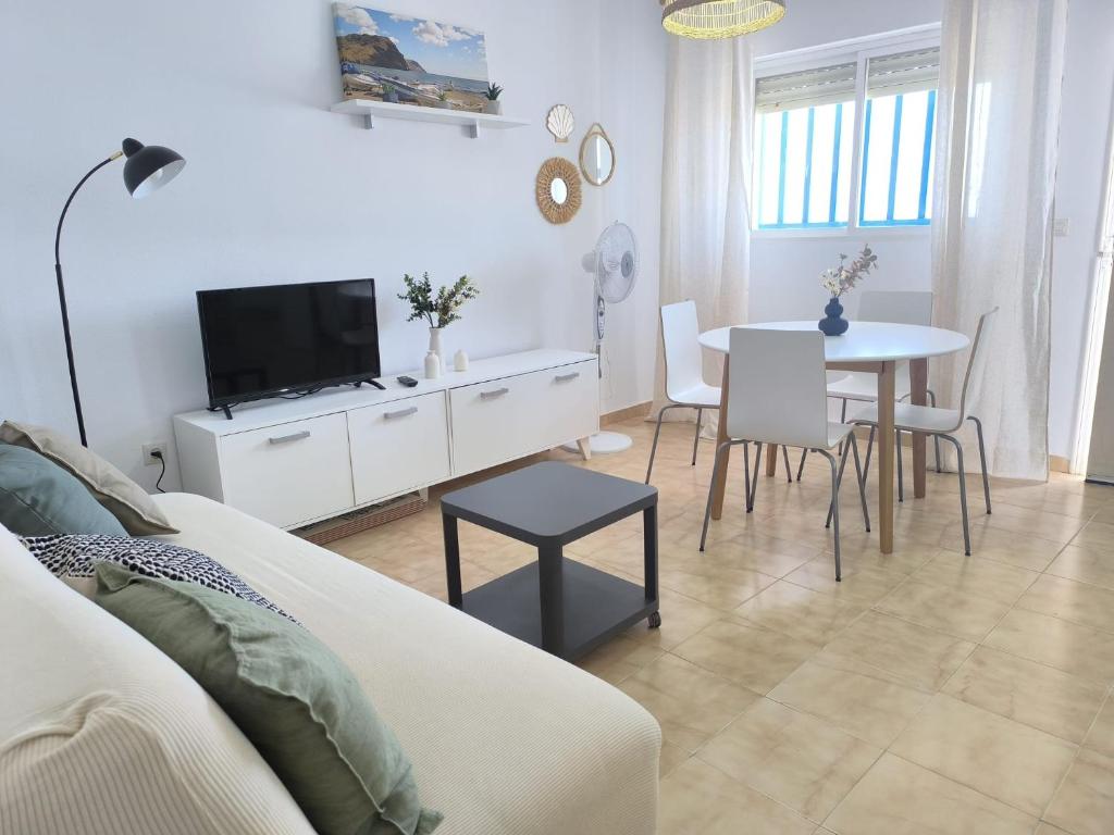 a white living room with a table and a tv at Apartamento Indalo en primera linea de playa in Las Negras