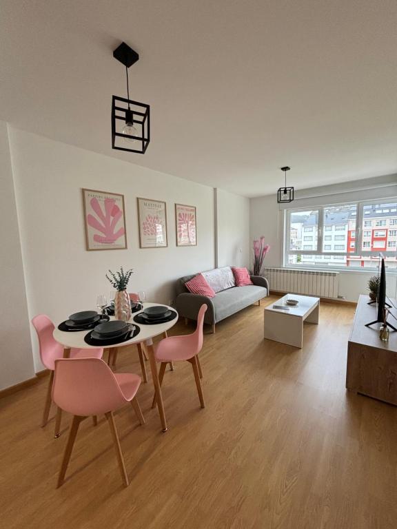 a living room with a table and pink chairs at Apartamento a pie de playa La Pepa in Burela de Cabo