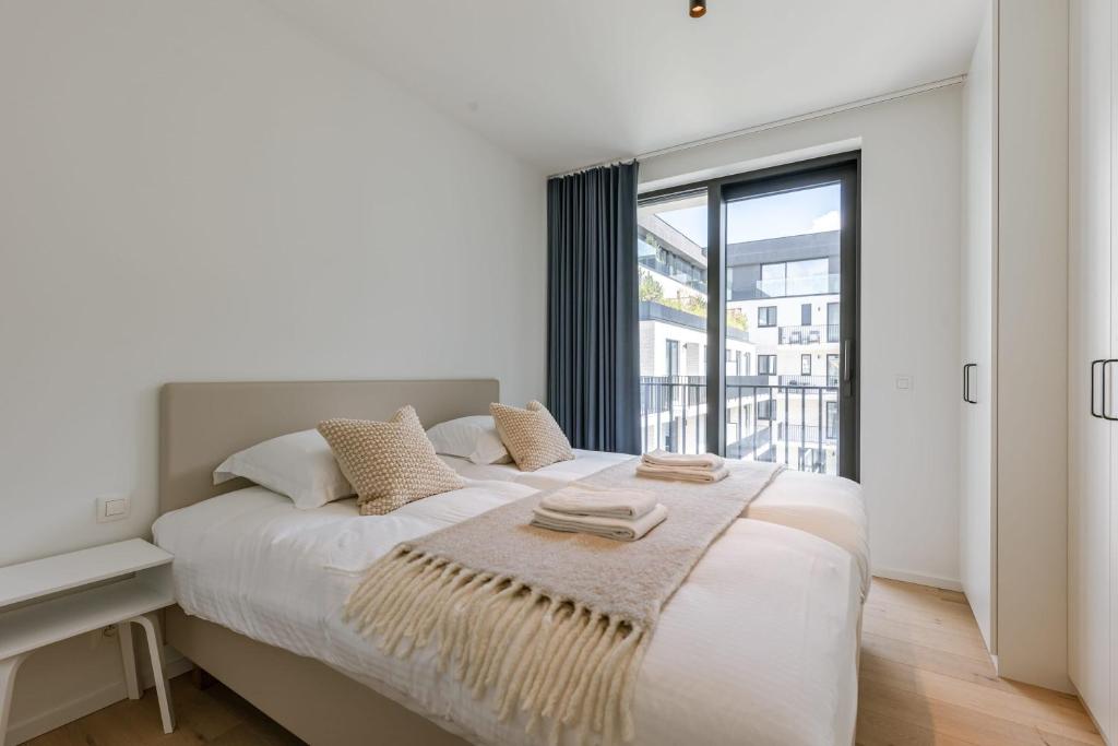 une chambre blanche avec un lit et une grande fenêtre dans l'établissement Huswell - Apartment with Terrace in the Heart of Nieuwpoort, à Nieuport