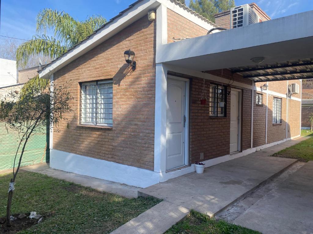 a brick house with a white door and a porch at Casa Ayacucho in Alta Gracia