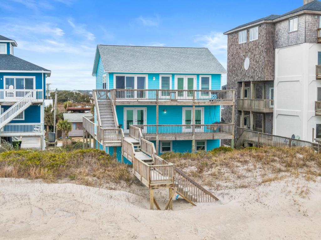 a house on the beach next to a building at Renegade - Oceanfront and Allows Pets! in Surf City