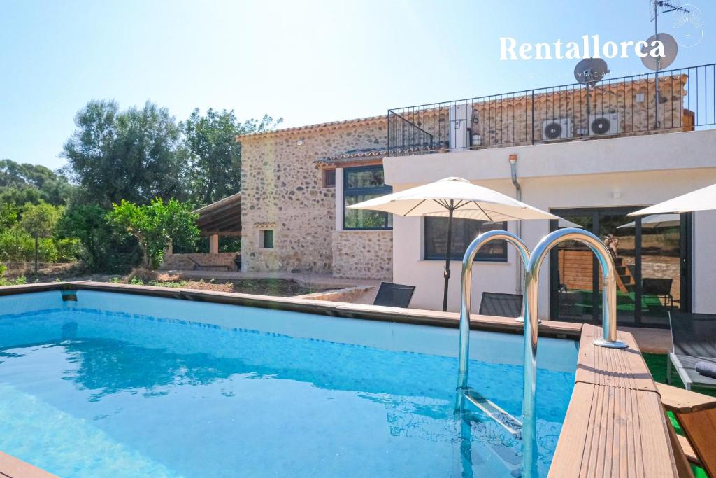 a swimming pool with an umbrella next to a house at Ses Rotes by Rentallorca in Campanet