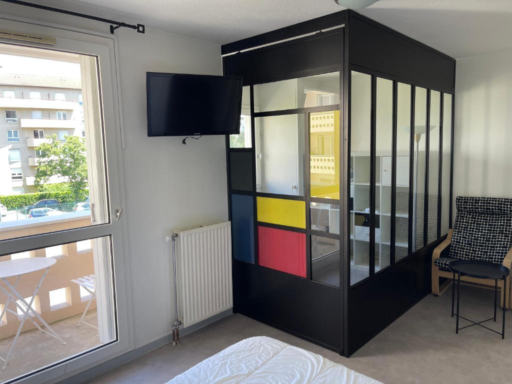 une armoire noire avec des portes en verre colorées dans une pièce avec une fenêtre dans l'établissement A l'Atelier Montplaisir, à Lyon