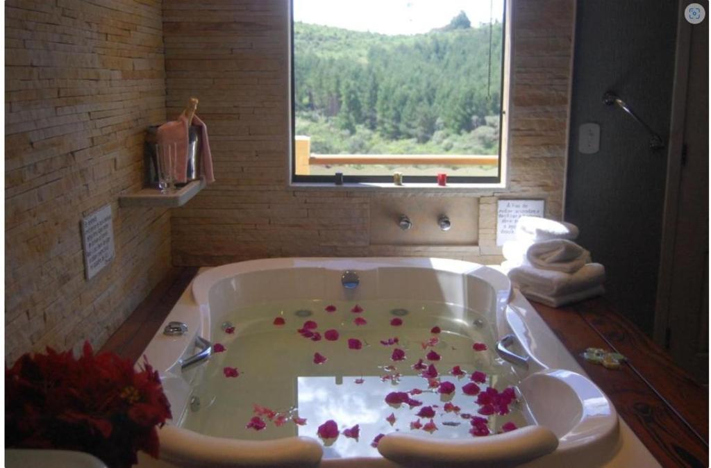 a bathroom with a tub with flowers on the floor at Pousada Bela vista Monte Verde in Monte Verde
