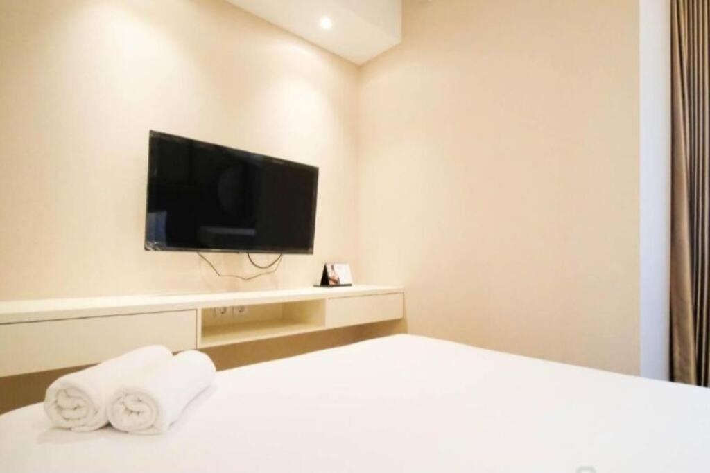 a room with a bed with a television and towels at Amazing 2BR Benson Apartment in Pakuwon mall in Surabaya