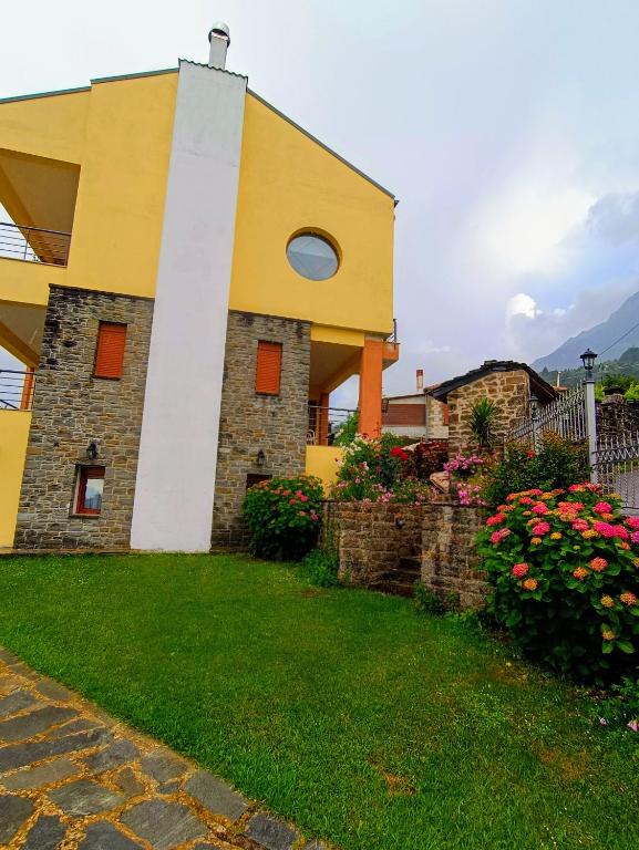 a yellow and white building with flowers in a yard at ΑΡΧΟΝΤΙΚΟ ΜΑΝΤΕΙΟ in Manteio