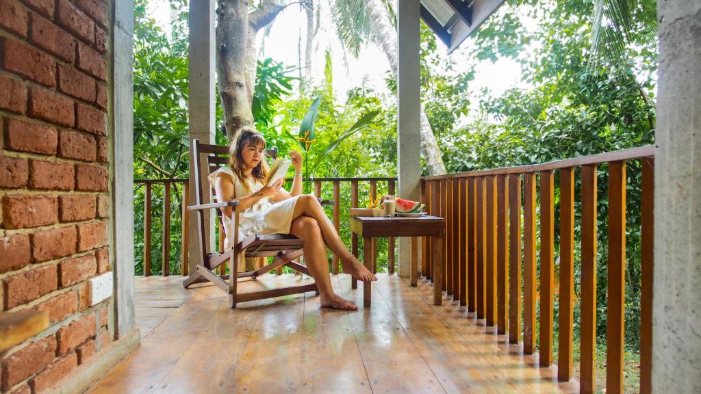 a woman sitting in a chair on a porch at Eco Breeze - Unawatuna in Galle