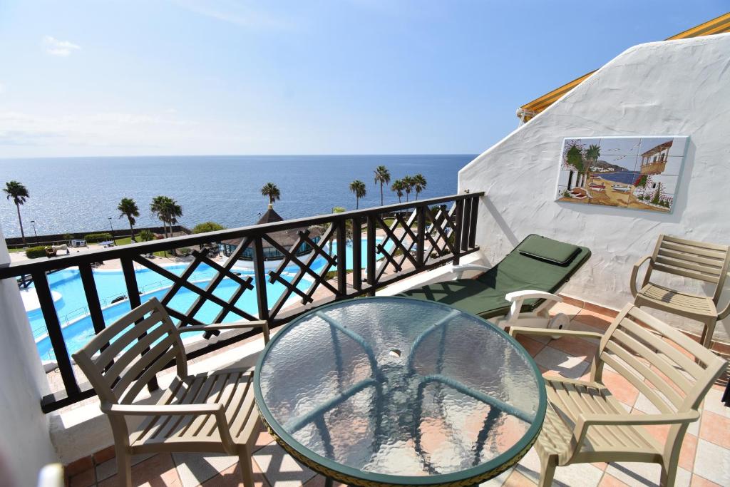 a balcony with chairs and a glass table and the ocean at Rocas del Mar 408 in Costa Del Silencio