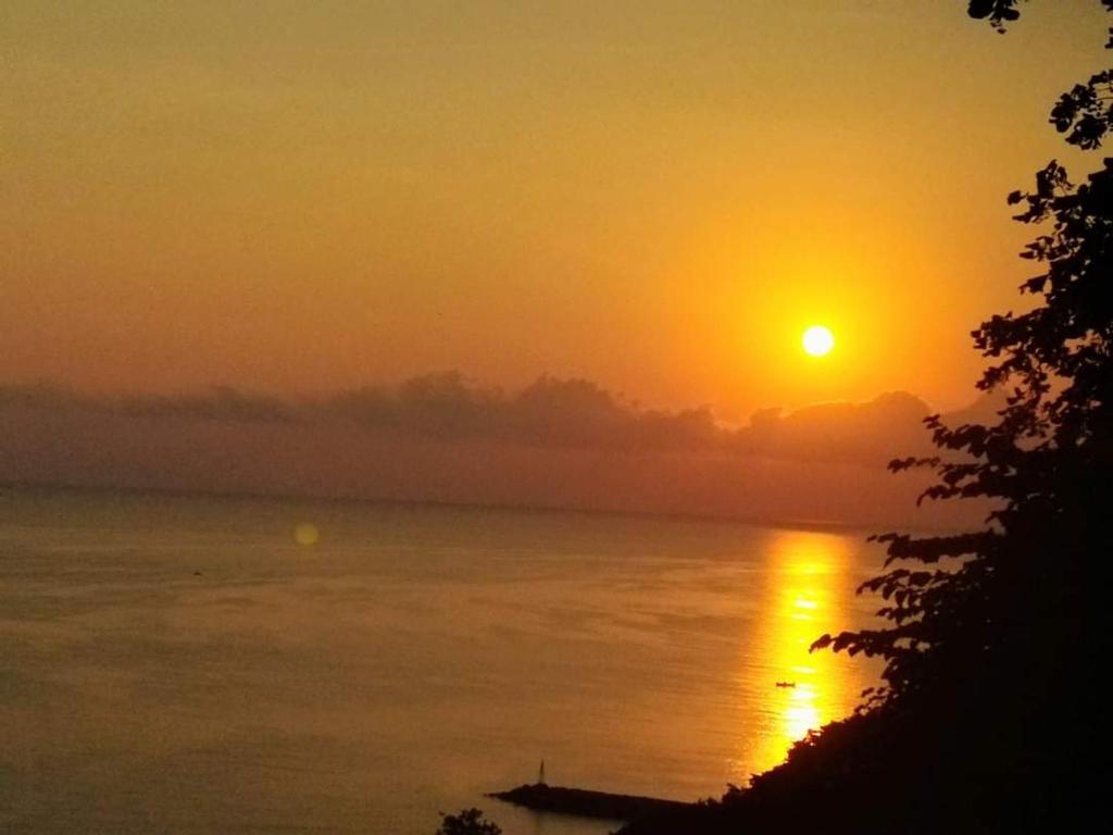 ein Sonnenuntergang über einem Gewässer bei Sonnenschein am Himmel in der Unterkunft Με Θεα!! in Stomio
