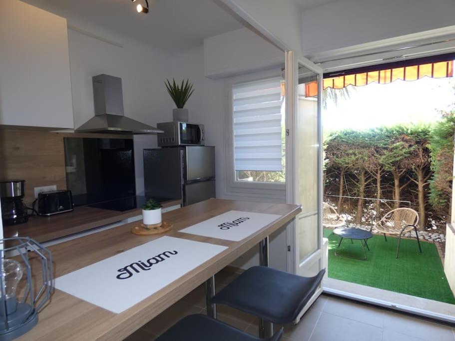 a kitchen with a counter and a table and a window at Studio moderne en rez de jardin in Antibes