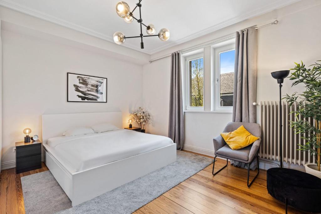 a white bedroom with a bed and a chair at Elegant 3BR Home in Prime Limpertsberg Location in Luxembourg