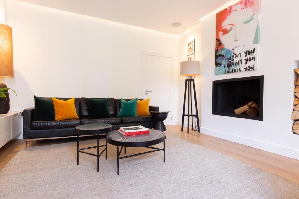 a living room with a black couch with colorful pillows at The Greyfriars Apartment in St. Andrews