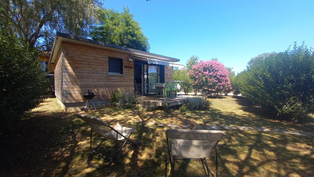 une petite maison avec deux chaises dans la cour dans l'établissement Gite ORCHIDEE au domaine les tournesols, à Mouzens