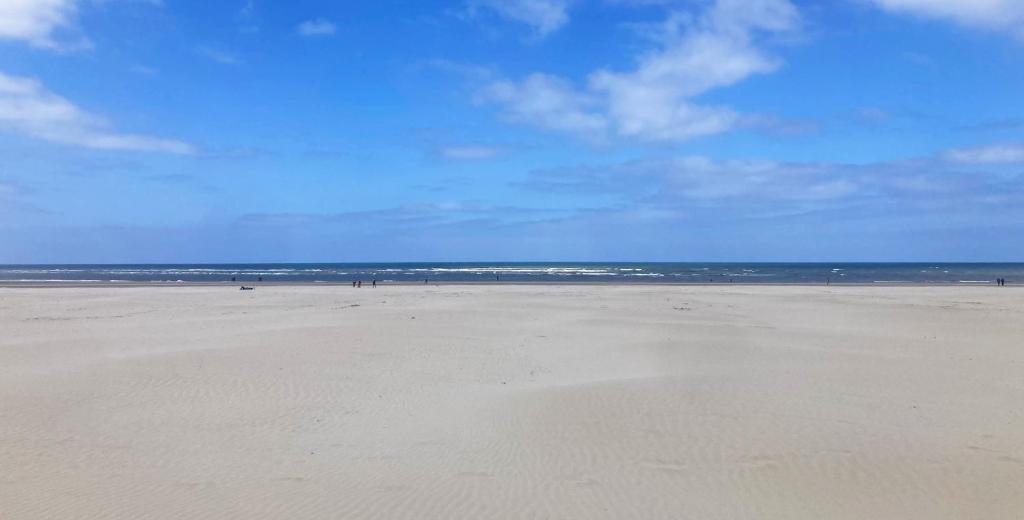 une plage vide avec des gens qui marchent sur le sable dans l'établissement Rooftop terrasse vue phare et mer, à Berck-sur-Mer