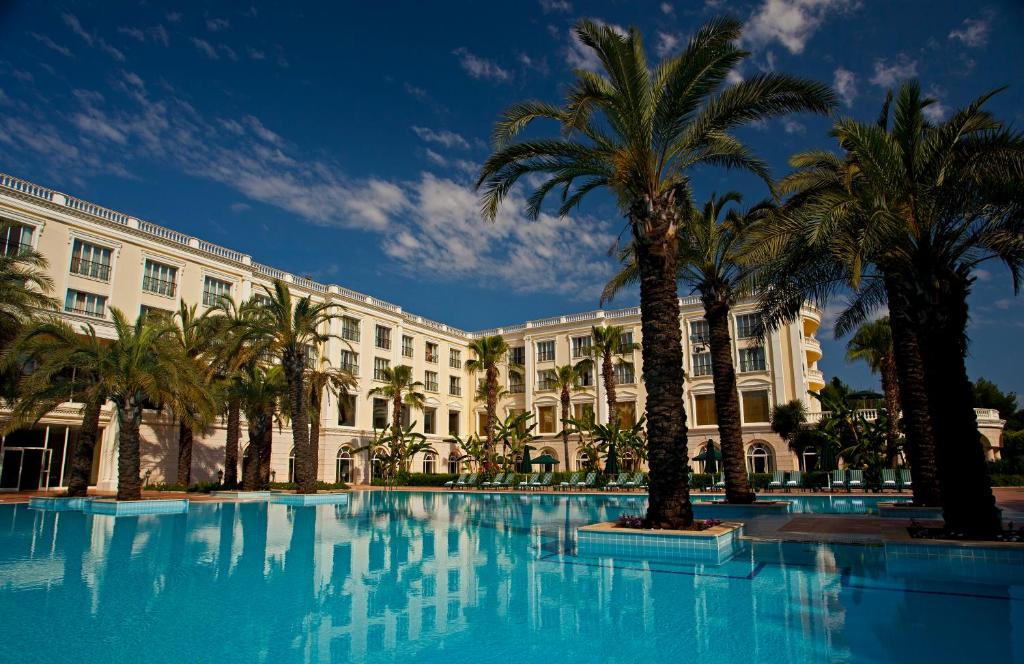 a large swimming pool with palm trees in front of a building at IC Hotels Airport in Antalya