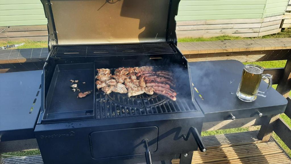 a grill with meat and a glass of beer at Lochview Retreat Caravan in Balminnoch