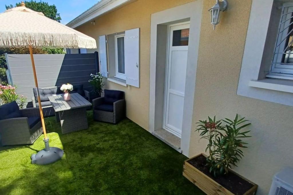un patio avec une table et un parasol dans l'établissement Appartement 2 pièces, 1 chambre, terrasse, à Gujan-Mestras