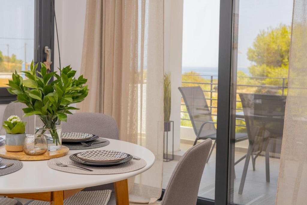 a dining room with a table and chairs and a balcony at Ammira Mare Apartment in Agia Pelagia
