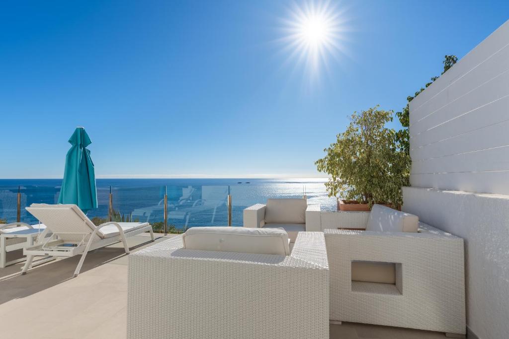 a balcony with white furniture and a view of the ocean at Maryvilla Inspiración y Vacaciones - Bungalows in Calpe