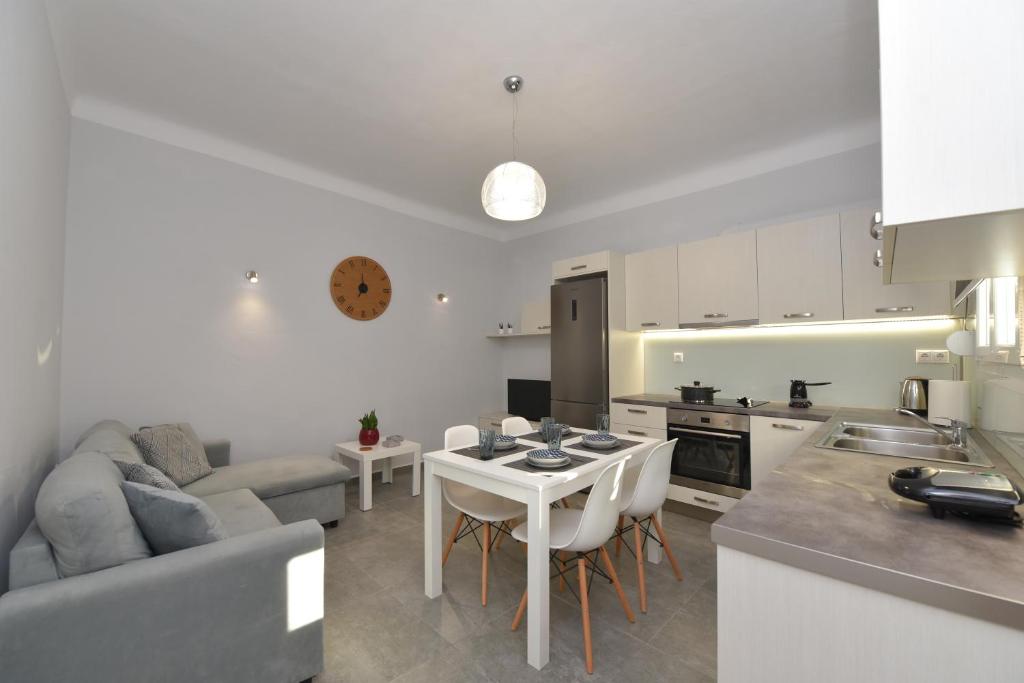 Una cocina y una sala de estar con una mesa y un sofá. en Cyclamen Hermoupolis, en Ermoupoli