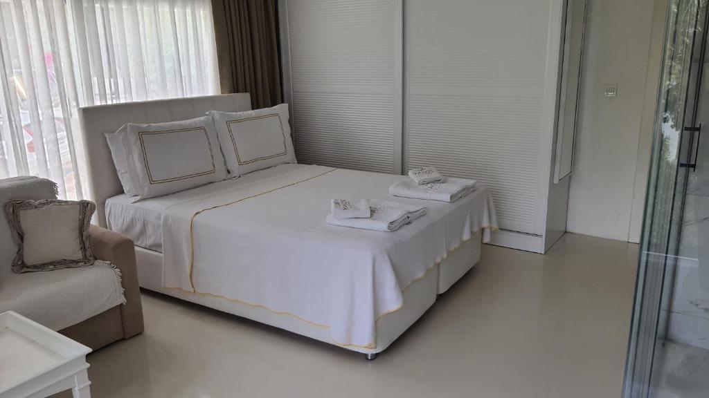 a white bedroom with a bed and a chair at Yasos Suites in Çeşme