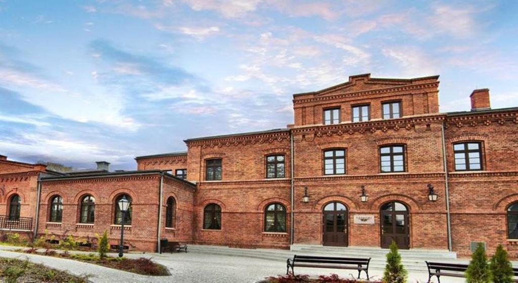 a large brick building with two benches in front of it at Resursa in Żyrardów