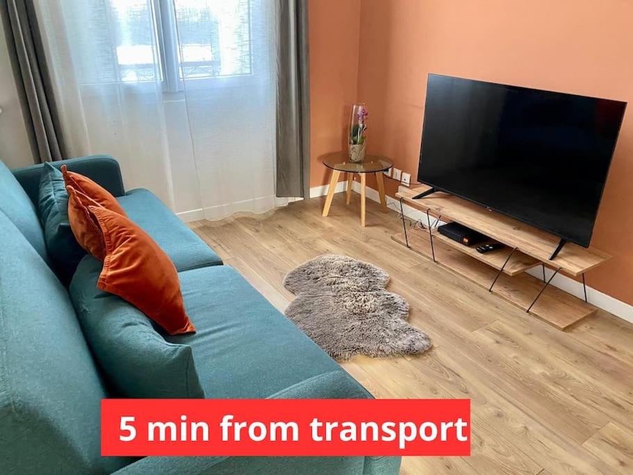 un salon avec un canapé bleu et une télévision à écran plat dans l'établissement Appartement Colombes - 12min de PARIS, à Colombes