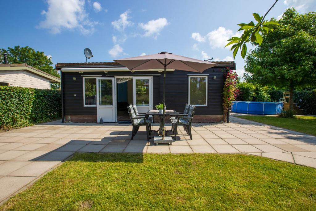 a patio with a table and an umbrella at Jamies Cottage Warmenhuizen nu met airco in Warmenhuizen