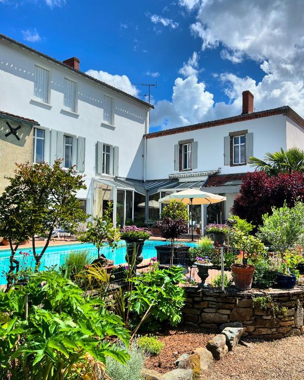 un grand bâtiment blanc avec une piscine dans l'établissement Le Relais du Puy, à Saint-Fulgent