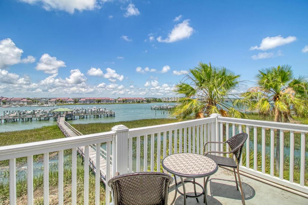 a balcony with two chairs and a table with a view of the water at 16 Turtle Bay Riverview Pool in Folly Beach