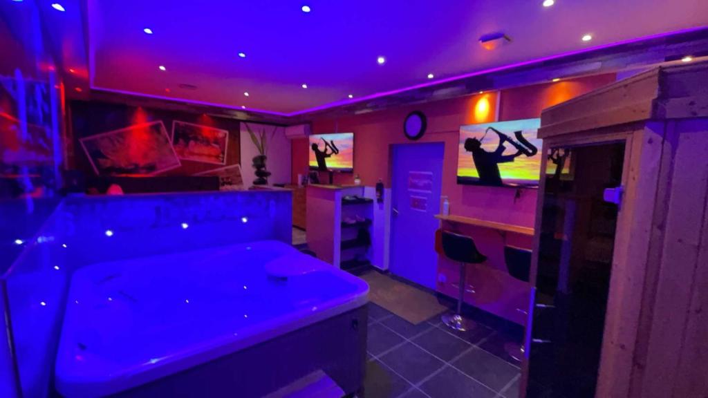 une pièce violette avec un homme jouant à un jeu vidéo dans l'établissement California love spa, à Lille