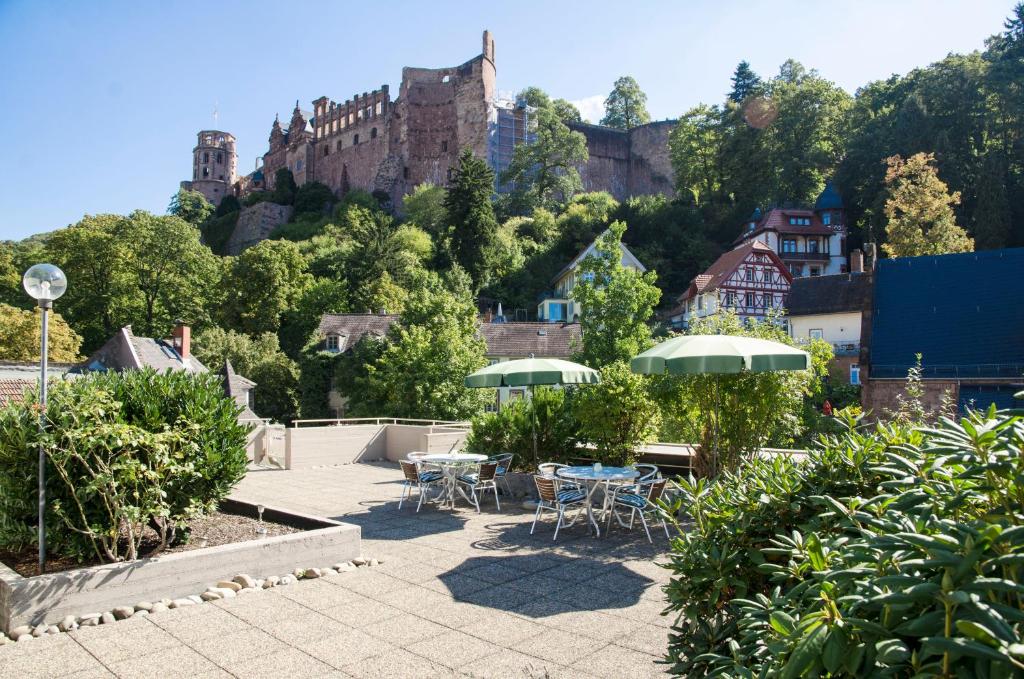 eine Terrasse mit Tischen und Stühlen und einem Schloss im Hintergrund in der Unterkunft Hotel am Schloss in Heidelberg