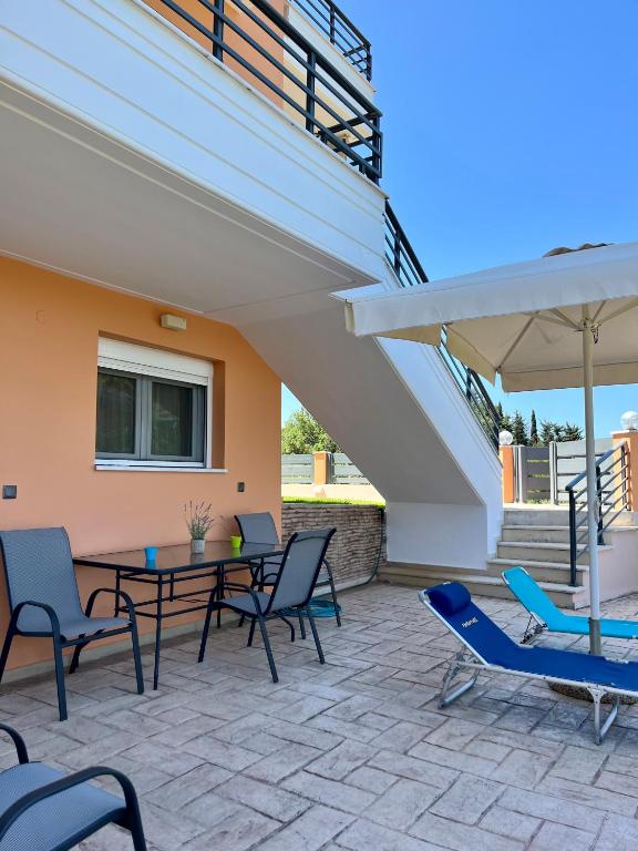 a patio with chairs and a table and an umbrella at Aspasia Apartment in Kanali