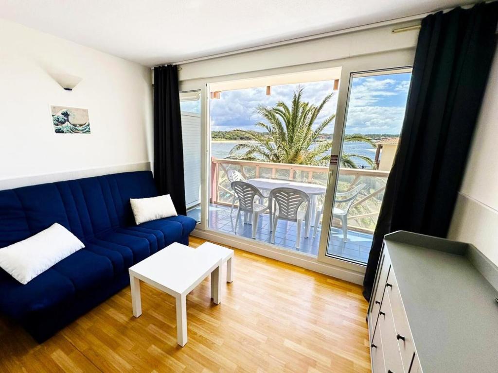un salon avec un canapé bleu et un balcon dans l'établissement Résidence Le Boucanier - 2 Pièces pour 4 Personnes 291, à Vieux-Boucau-les-Bains