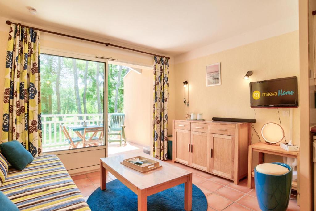 un salon avec un canapé, une table et une télévision dans l'établissement Le Domaine du Golf de Pinsolle - maeva Home - Appartement 2 pièces 3 personnes - Prestige MAE-4431, à Soustons