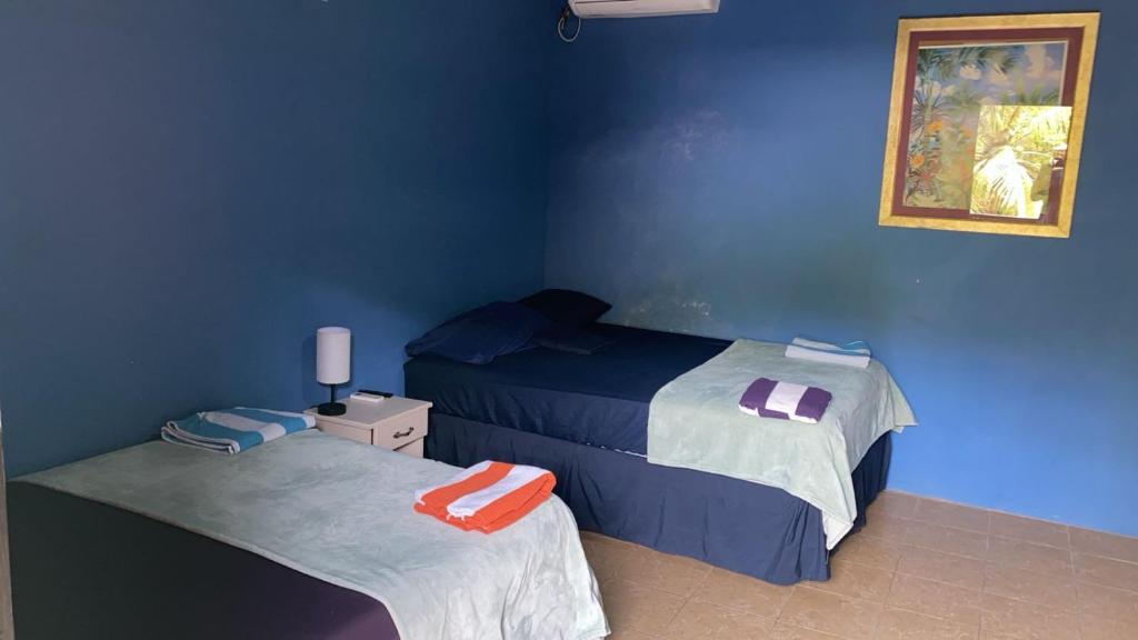 a bedroom with two beds and a table with a lamp at Airport Inn Roatan in Coxen Hole
