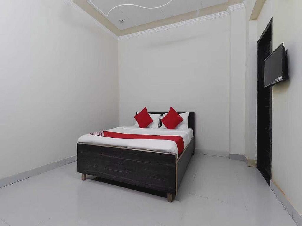 a bedroom with a bed with red pillows and a tv at OYO Flagship A Hospitality in Lucknow