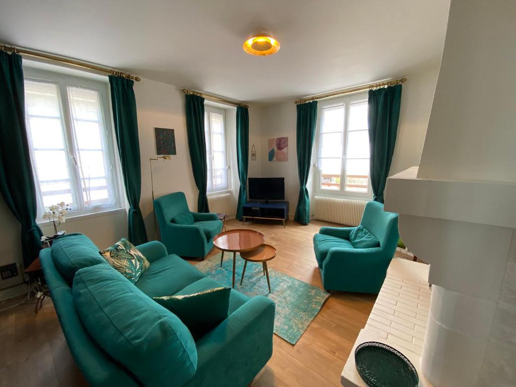 a living room with a green couch and chairs at Appartement duplex Luc sur Mer, en face de la plage in Luc-sur-Mer