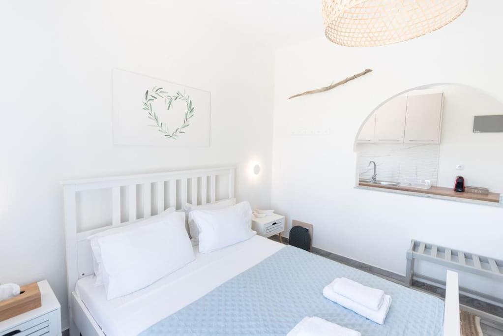 a white bedroom with a bed and a mirror at Swell S1 maisonette in Naousa in Naousa
