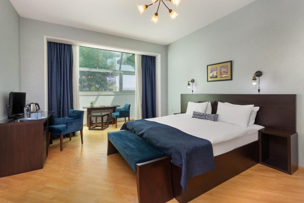 a bedroom with a bed and a desk and a window at Hotel Bella Casa in Tbilisi City