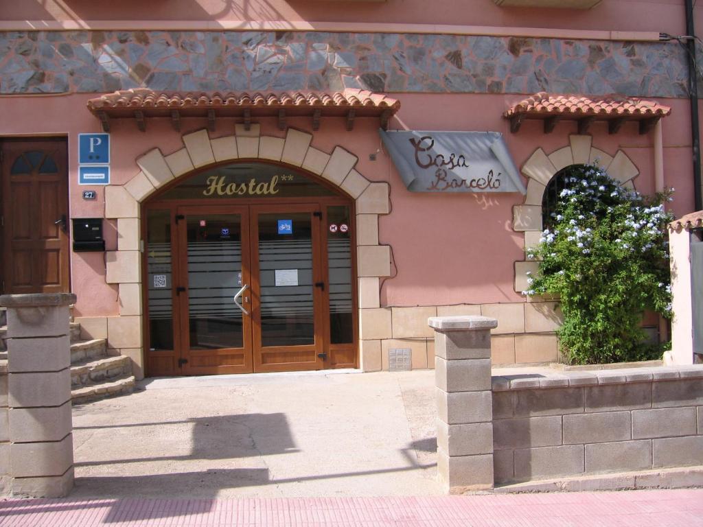 ein Geschäft vor einem rosa Gebäude mit Holztüren in der Unterkunft Hostal Casa Barcelo in Horta de San Joan