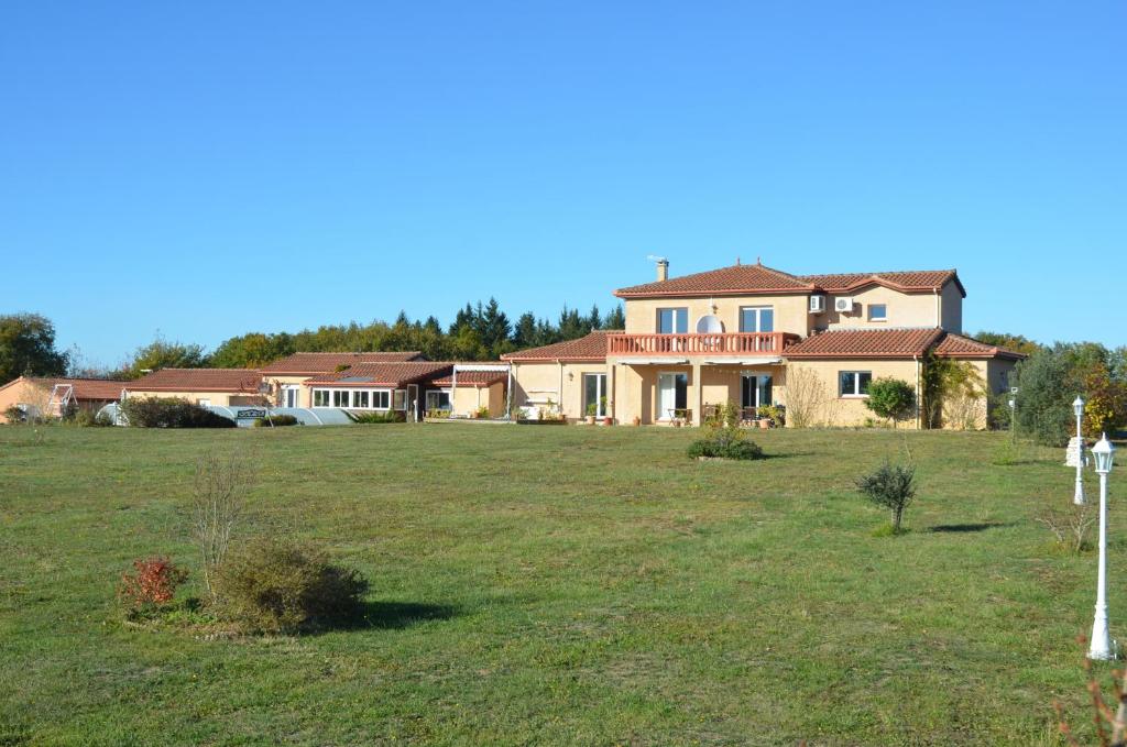 une grande maison dans un champ avec une cour dans l'établissement La Batterie, à Lagarde-Hachan