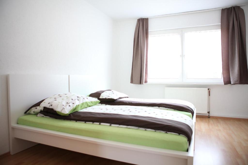 Bett in einem weißen Zimmer mit Fenster in der Unterkunft Apartment Am Ring in Bochum