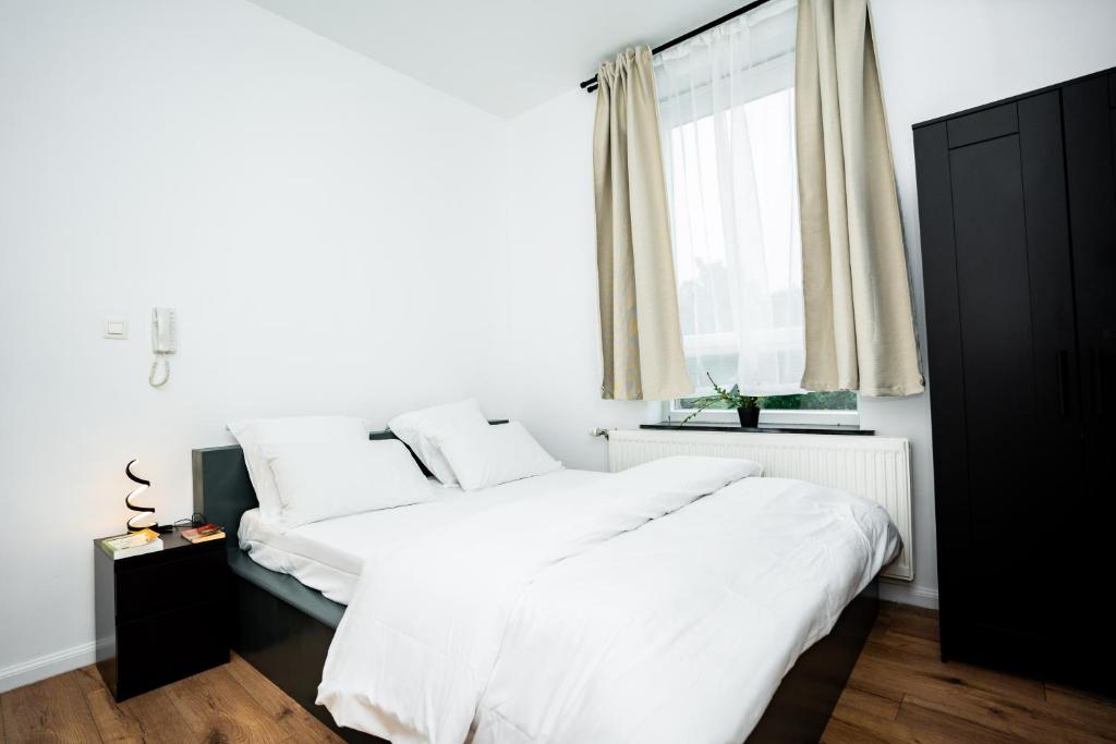 a bedroom with a large white bed and a window at Chambre R1 avec salle de bain partagée près de l'hôpital de la Citadelle à Liège in Liège