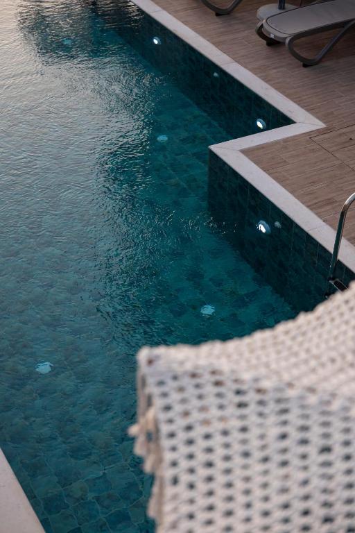 a swimming pool with a wicker chair and some water at Diol Hotel Ksamil in Ksamil